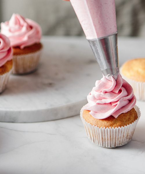 A tiny cupcake receives a pink icing swirl